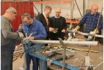 Während die Schweißer an ihren Projekten arbeiten, lässt sich Oberbürgermeister Alexander Badrow (3.v.l.) von Geschäftsführer Ulf Ahrens ein Werkzeug erläutern, mit dem die Rohre auf absolute Genauigkeit überprüft werden.